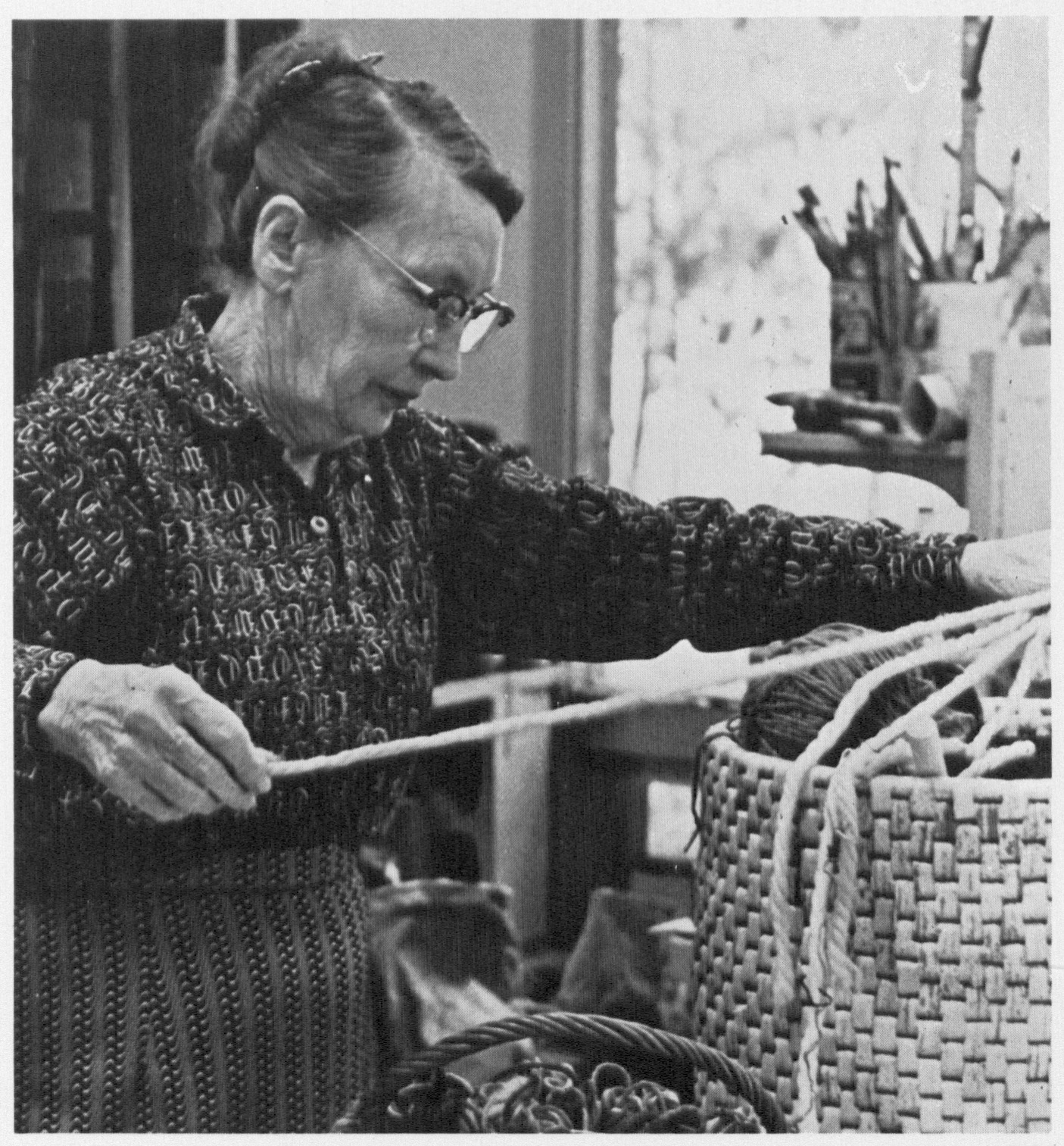 In her studio, Memphis Wood measures out a length of chord from a basket full of yarn and other materials.